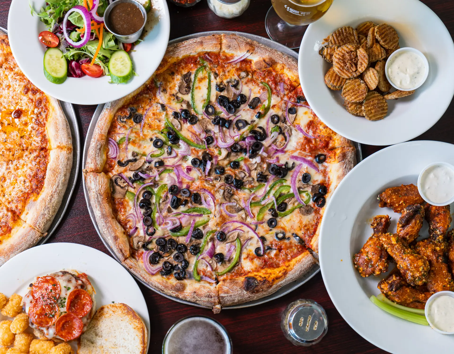 Wide overhead of the pub menu spread — pizza, wings, salad and sides