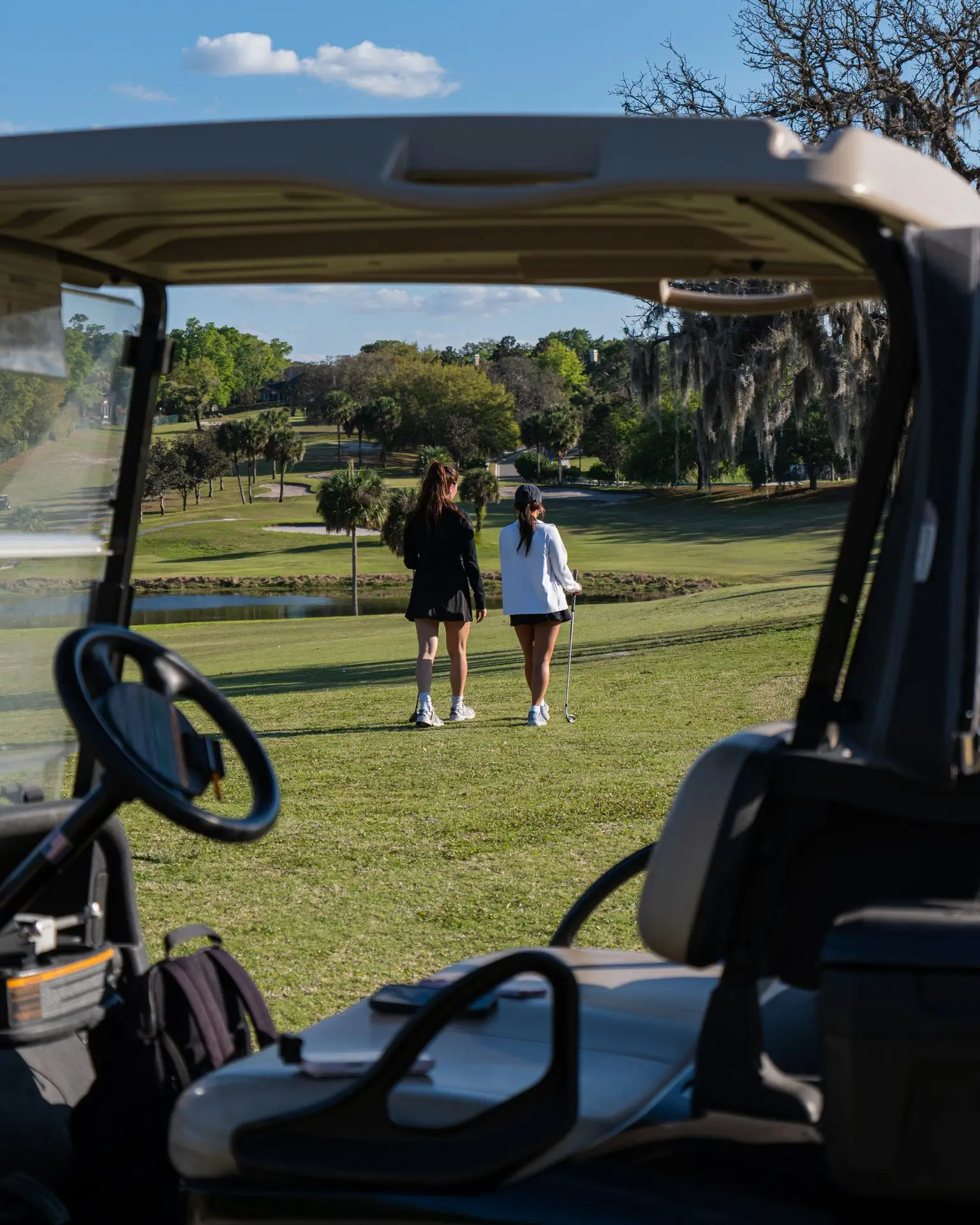 Golfers walking the fairway seen from a cart