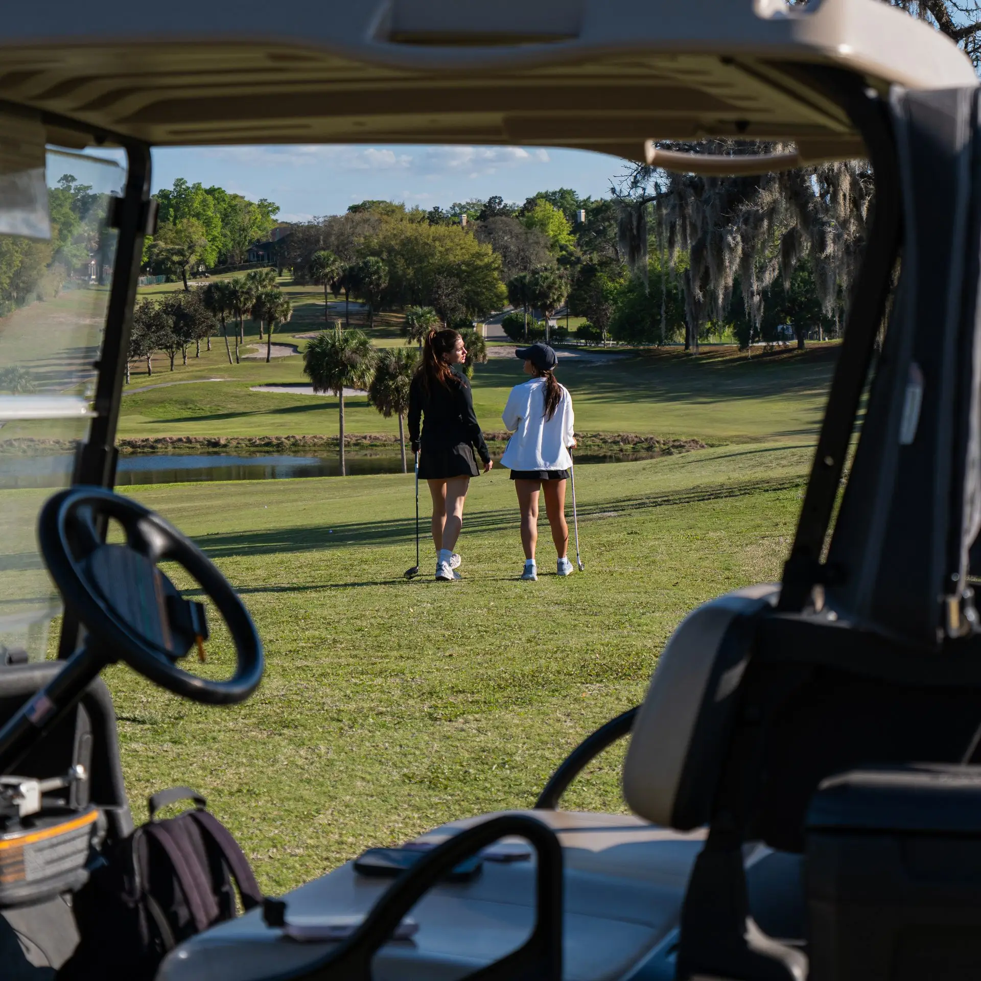Two golfers on the course viewed from a cart