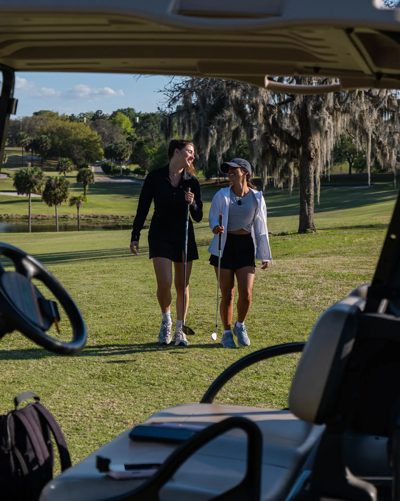 Golfers walking up the fairway under mature oaks