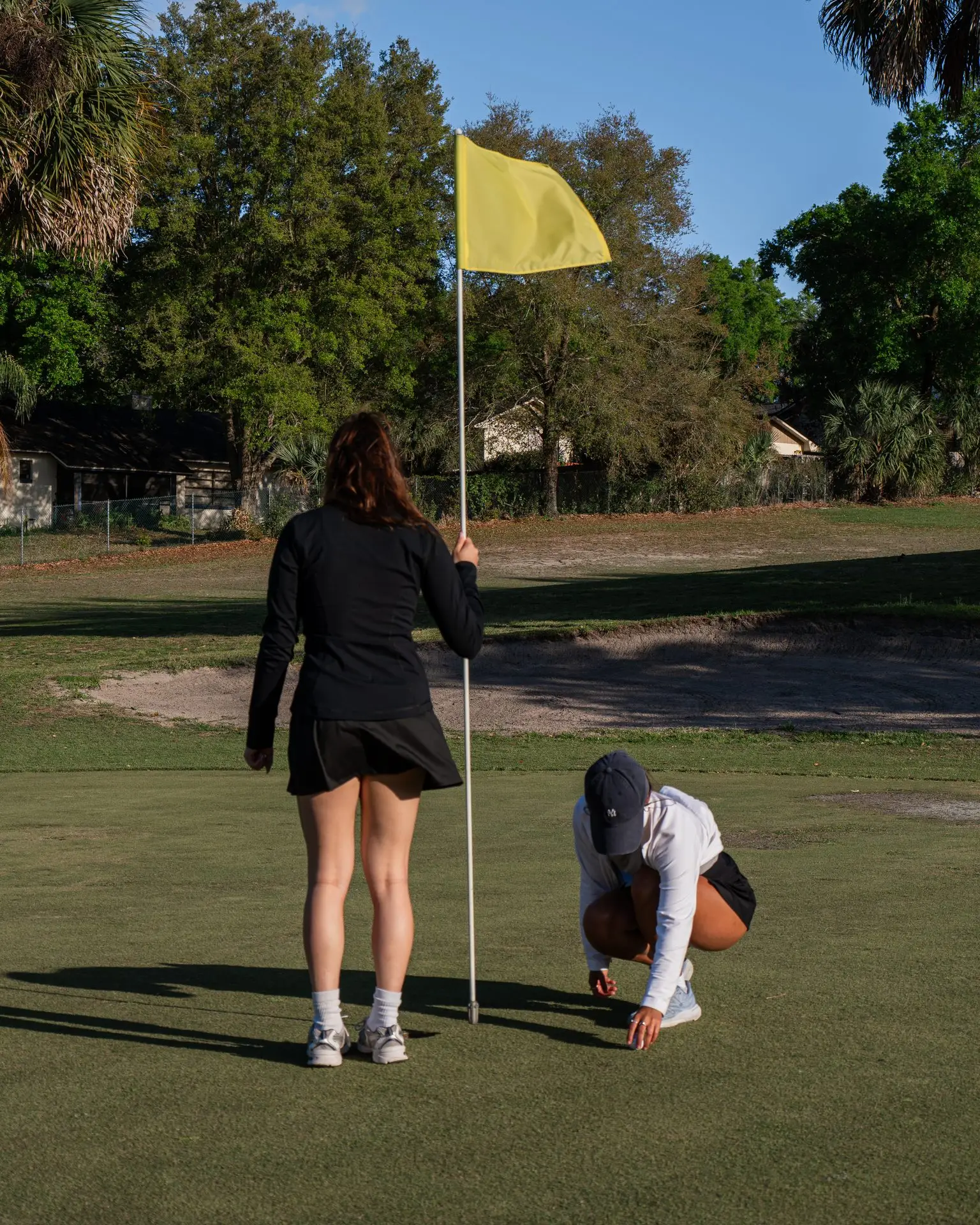 Golfers tending the flag on the green